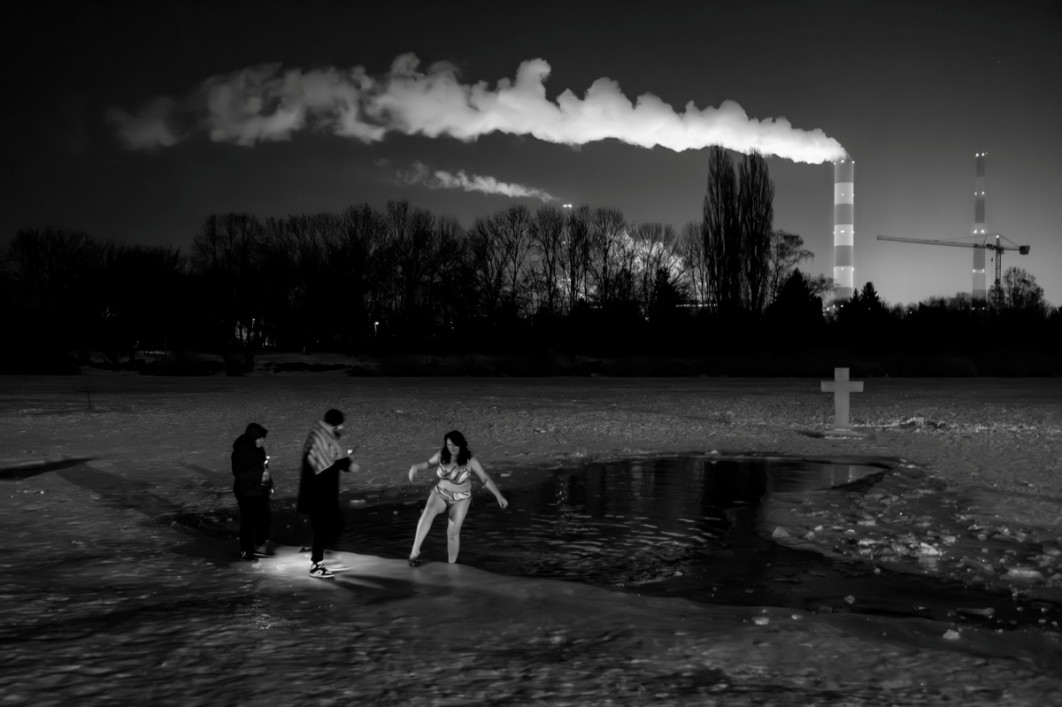 Fot. Taida Tarabuła, z serii "Feast of Jordan", 3. miejsce w profesjonalnej kategorii Photojournalism / Fine Art Photography Awards 2026<br></br>Warszawa, Polska, 19 stycznia 2026 r. - prawosławne święto Jordanu nad Jeziorkiem Czerniakowskim. Każdego roku 19 stycznia Kościoły prawosławny i greckokatolicki obchodzą święto Jordanu, znane również jako Teofania. Podczas uroczystości odbywa się poświęcenie wody oraz tradycyjny chrzest. Ponieważ tegoroczny styczeń był wyjątkowo mroźny, symboliczny chrzest miał miejsce w lodowatej wodzie. W ceremonii uczestniczyli wierni obu Kościołów, w tym wielu uchodźców z Ukrainy. Wielu mieszkających w pobliżu Polaków przyszło obserwować tę niezwykłą uroczystość.