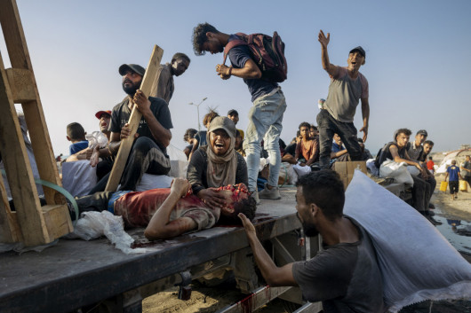 Fot. Saher Alghorra, The New York Time, Pulitzer Prize in Breaking News Phoography 2026„Mój syn, mój syn” — krzyczała kobieta, gdy ciężarówka wiozła ją i jej rannego syna do szpitala Hamad w północnej Gazie. Chłopiec został postrzelony, kiedy próbował zdobyć pomoc w pobliżu przejścia Zikim między Gazą a Izraelem - historii takich jak ta było coraz więcej wraz z postępem wojny. Izraelskie ograniczenia dotyczące pomocy humanitarnej sprawiały, że zdesperowani ludzie regularnie ryzykowali życie, próbując zabrać żywność z ciężarówek albo ustawiając się w kolejkach w punktach dystrybucji pomocy. Setki Palestyńczyków zginęły, szukając pomocy, nawet gdy w północnej Gazie ogłoszono głód. Syn kobiety próbował zdobyć pomoc właśnie z tej ciężarówki - tej samej, która teraz wiozła go do szpitala. (14.08.2025)