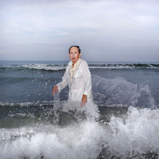 Ana Nance, „Ostatni portret Mary Kay”, North Myrtle Beach, Południowa Karolina, USA.

Na południu Stanów Zjednoczonych wciąż kultywowany jest religijny rytuał baptystycznego Chrztu. Osoba chrzczona, ubrana na biało, wchodzi do wody, by oczyścić ciało i duszę. Na zdjęciu jest moja macocha Mary Kay, którą sfotografowałam w miejscu, w którym spędziłam wiele radosnych chwil dzieciństwa. Ten portret jest też hołdem dla mojego ojca, próbą odtworzenia zdjęcia, które zrobiłam mu wiele lat temu, tuż przed jego śmiercią. Ten chrzest nie ma nic wspólnego z religią - to pielęgnowanie pamięci, miłości i wdzięczności. To mój własny rytuał. Kay również zmarła na raka w październiku tego roku. To jest jej ostatni portret.
