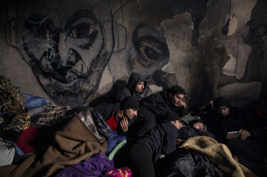 fot. Alessio Paduano, Migranci z Afganistanu i Pakistanu oglądają na smartfonie mecz piłki nożnej w opuszczonym budynku w Bihacu w Bośni i Hercegowinie, 21 stycznia, 2021 roku.