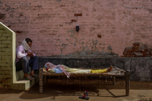 Mężczyzna przesiaduje obok chorej żony w prowizorycznej klinice w wiosce Parsaul, w stanie Uttar Pradesh w Indiach, 22 maja 2021 r. fot. Adnan Abidi, Reuters / The Pulitzer Prize 2021 for Feature Photography