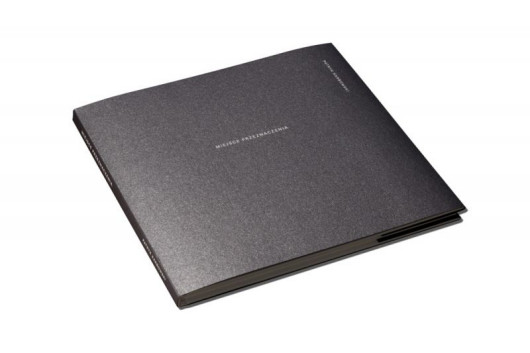 Patryk Karbowski, Miejsce przeznaczenia, Brązowy medal w profesjonalnej kategorii Photobook.

Szacuje się, że ponad połowa mieszkańców Warszawy urodziła się poza nią. Dla wielu młodych ludzi w Polsce migracja do dużego miasta jest naturalnym etapem rozwoju i jedyną możliwością awansu.

Fragment tekstu Marty Szarejko zamieszczonego w książce: Czasami liczą się drobiazgi: kolor skarpet chłopaka, który siedzi na stołku z Ikei i melancholijnie patrzy w dal; smętny sweter wiszący na suszarce w szaroburym świetle; deska do prasowania przy telewizorze; brak min na twarzach wystrojonych dziewczyn wpatrzonych w ekrany telefonów. Albo lampa przy prawie pustej półce. […] Już prawie to wyparłam: przyjezdni żyją wśród innych przyjezdnych. Do tego zupełnie inaczej niż ludzie stąd.