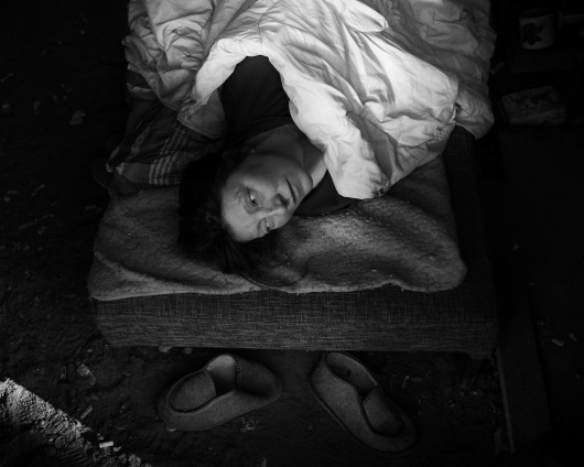 Fot. Maciej Grzybowski, 1. miejsce w kat. Documentary Project / Grand Press Photo 2024Ela, Darek i Mirek są w bezdomności od wielu lat. Mieszkają w lesie nad rzeką, na obrzeżach miasta. Opiekują się dwoma psami Florą i Jogim. Ela przez kilkanaście lat pracowała w zakładach farmaceutycznych. Jest wdową, jej syn mieszka za granicą. Obecnie bezrobotna. Darek, partner Eli, podejmuje się prac dorywczych na budowach i w firmach sprzątających miasto. Sam zbudował wszystkie domki. Mirek pochodzi z Pomorza, jest wolnym duchem. Często wychodzi w nocy zbierać złom, który potem sprzedaje.
W Polsce około 30 tysięcy osób znajduje się w kryzysie bezdomności, z czego ponad 80 proc. stanowią mężczyźni.
