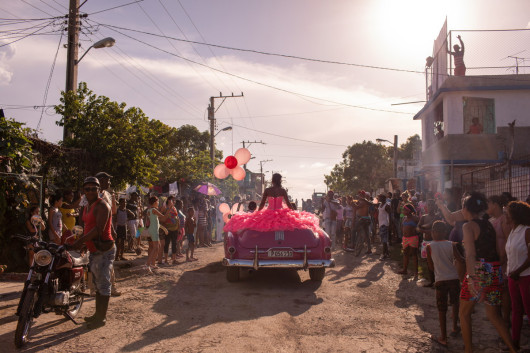 fot. Diana Markosia, Magnum Photos, The Cubanitas, 1. miejsce w kategorii Contemporary Issues.

15 urodziny w kulturze latynoskiej oznaczają wejście kobiety w dorosłość. Rodziny urządzają z tej okazji kosztowne przyjęcia, a solenizantki ubierane i traktowane są jak księżniczki. Na Kubie tradycja ta wyewoluowała w przedstawienie w skład którego wchodzą sesje zdjęciowe i wideo. Na zdjęciu 15-letnia Pura podróżująca przez swoją dzielnicę w kabriolecie z lat 50., otoczona przez mieszkańców, którzy zebrali się, by świętować jej urodziny.