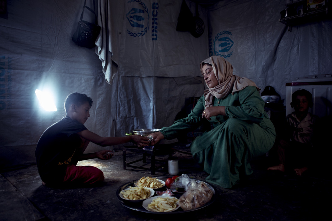 Fot. Rayna Carruthers, "A Mother's Care", Amsha Bushra  odbiera śmieci od syna, który pomaga jej przygotować lunch. Schronienie zbudowali Bushra i jej mąż, przy wsparciu innych mieszkańców obozu dla uchodźców. Przez ostatnie 12 lat Bushra pracowała w lokalnym centrum edukacyjnym dla uchodźców - praca ta pozwalała utrzymać jej rodzinę. Gdy jednak Syryjczyków zaczęto zachęcać do powrotu, a centrum zostało zamknięte, straciła źródło dochodu. W obliczu narastających trudności z opłaceniem jedzenia, czynszu i innych podstawowych potrzeb, rodzina przygotowuje się do powrotu do Syrii / Female in Focus x Nikon 2025