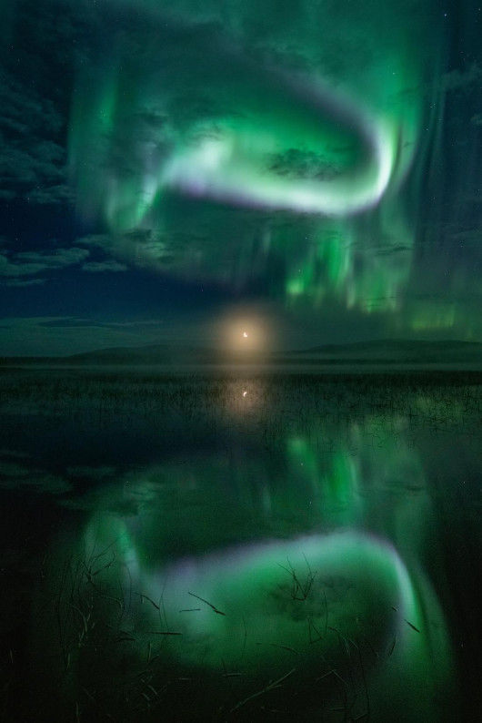 fot. Thomas Kast, Proper Welcome for the Moon, 2. miejsce w kategorii AuroraeByła cicha, spokojna noc. Obserwowałem wschód księżyca nad jeziorem, kiedy nagle zorza polarna stała się bardzo silna i zaczęła tańczyć na niebie. Nad jeziorem znajdowała się mgła, która otulała ten księżycowy spektakt.